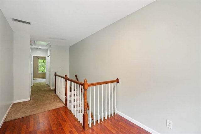 stairway with baseboards, attic access, visible vents, and wood finished floors