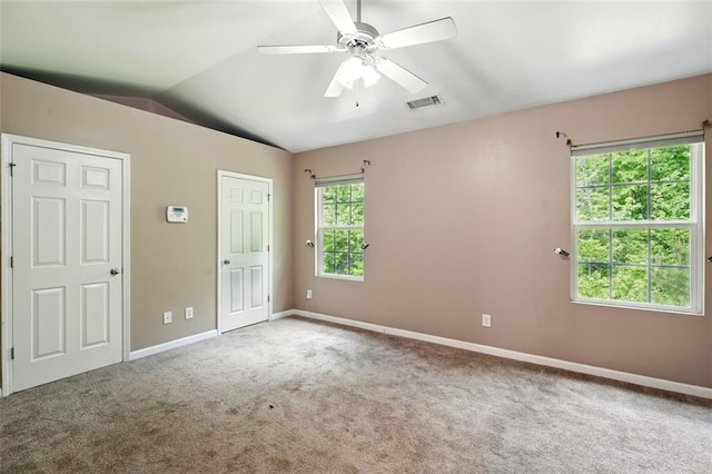 carpeted spare room featuring baseboards, ceiling fan, visible vents, and vaulted ceiling