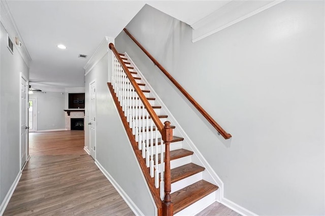 stairway with baseboards, a fireplace, visible vents, and wood finished floors