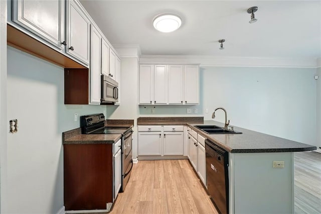 kitchen with a sink, a peninsula, black appliances, and dark countertops