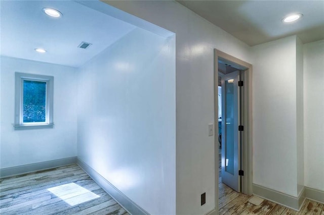 hall featuring light wood-type flooring, baseboards, and recessed lighting