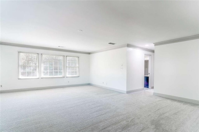 spare room with ornamental molding, light carpet, and baseboards