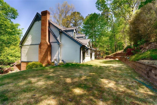 view of side of property with a yard and a chimney