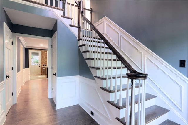 stairway featuring a decorative wall, wood finished floors, and wainscoting