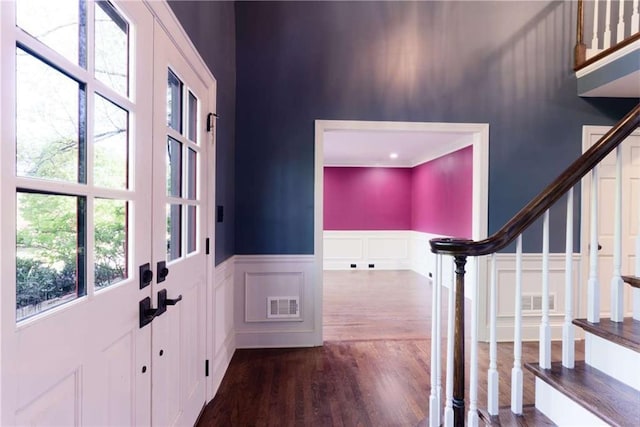 entryway featuring a decorative wall, plenty of natural light, dark wood-style flooring, stairway, and wainscoting