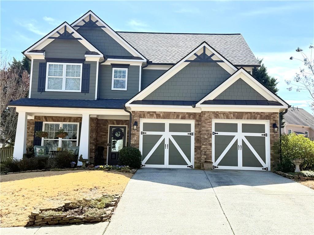 craftsman-style house with concrete driveway, a garage, stone siding, and roof with shingles