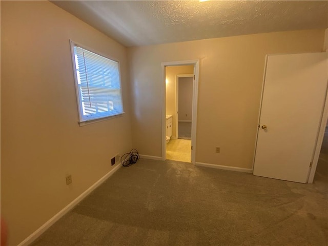 interior space featuring carpet floors, a textured ceiling, and ensuite bath