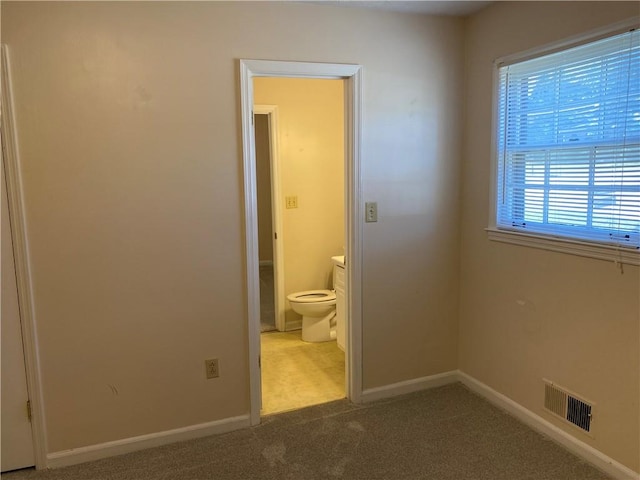 unfurnished bedroom featuring ensuite bathroom and carpet