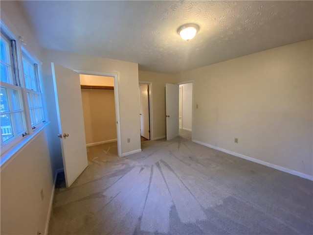 unfurnished bedroom with a spacious closet, carpet floors, a textured ceiling, and a closet