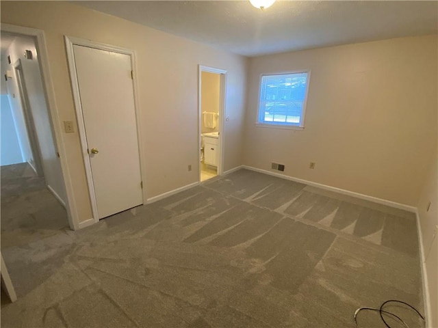 unfurnished bedroom featuring carpet, ensuite bath, and a closet