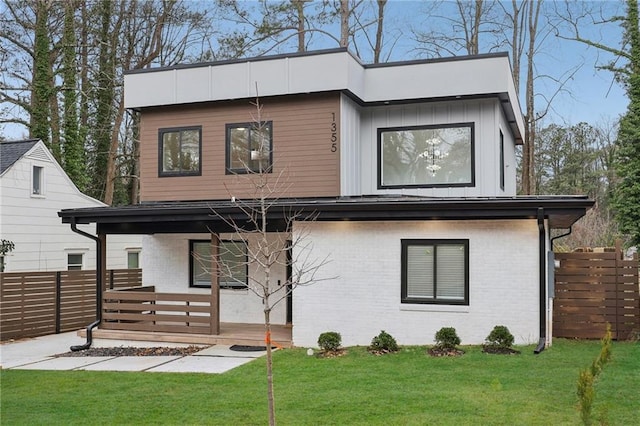 back of property featuring brick siding, a lawn, and fence