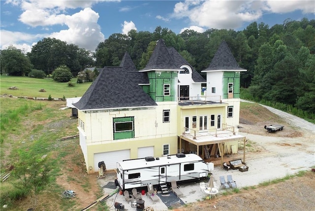 back of house featuring a balcony, a patio, a yard, and a garage