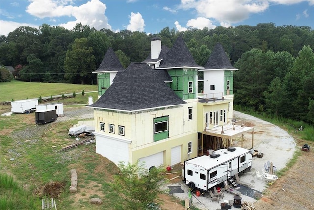 back of property with a lawn, a balcony, and a garage