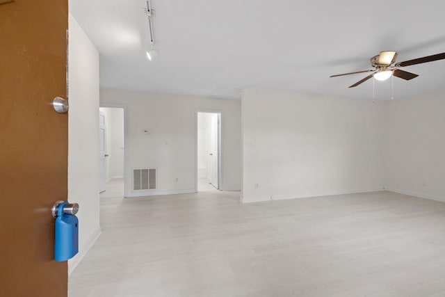 spare room featuring visible vents, track lighting, light wood finished floors, baseboards, and ceiling fan