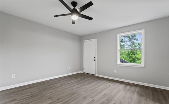 empty room featuring a ceiling fan, wood finished floors, visible vents, and baseboards