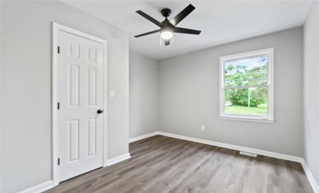 unfurnished room with a ceiling fan, baseboards, and wood finished floors