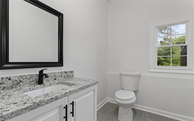 bathroom with toilet, tile patterned floors, baseboards, and vanity