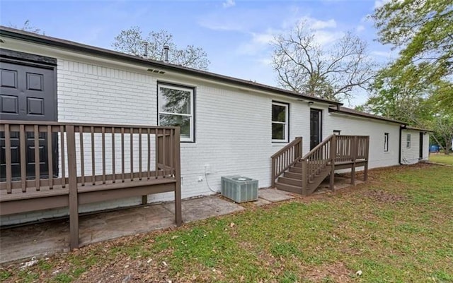 rear view of property with brick siding, a lawn, a deck, and central air condition unit