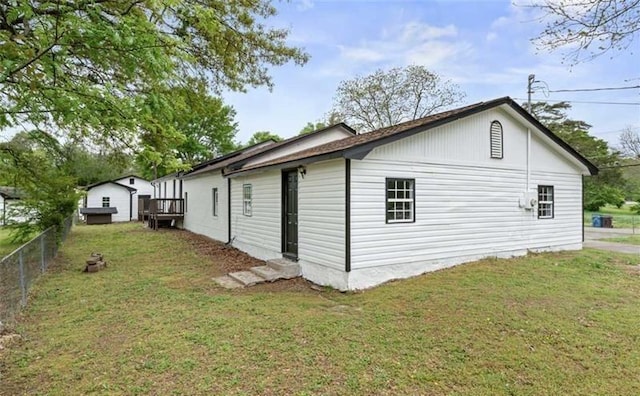 view of side of home featuring entry steps, fence, and a lawn