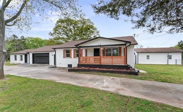 view of front of home with a garage, concrete driveway, covered porch, a front lawn, and brick siding