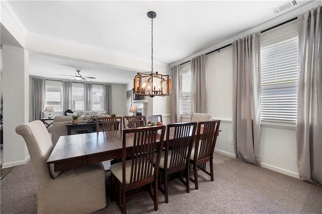 dining room with ceiling fan with notable chandelier, crown molding, and carpet