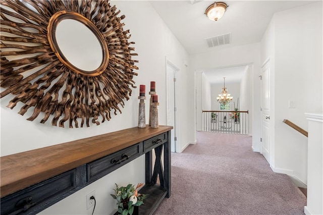 hall featuring light colored carpet and a notable chandelier