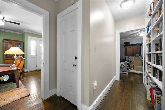 hall with dark wood-style flooring, baseboards, and ornamental molding