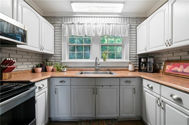 kitchen featuring range with electric stovetop, a sink, stainless steel microwave, and ornamental molding