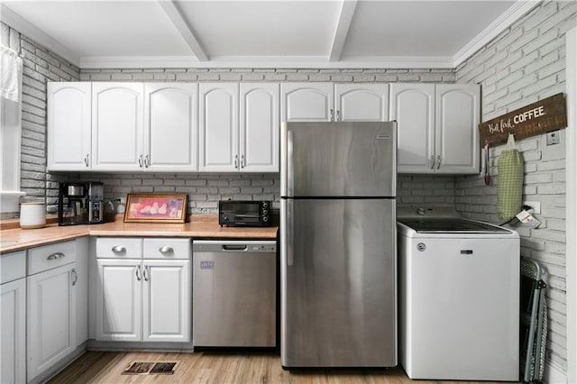 kitchen with white cabinets, appliances with stainless steel finishes, washer / dryer, and light countertops