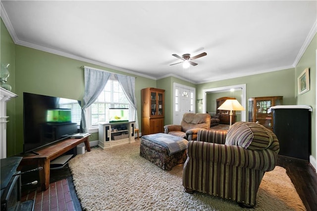 living room featuring baseboards, ornamental molding, ceiling fan, and a fireplace