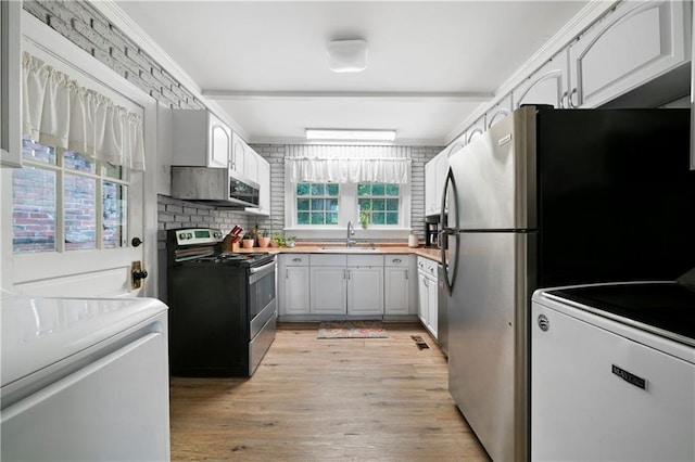 kitchen with appliances with stainless steel finishes, a sink, light wood-style floors, light countertops, and backsplash