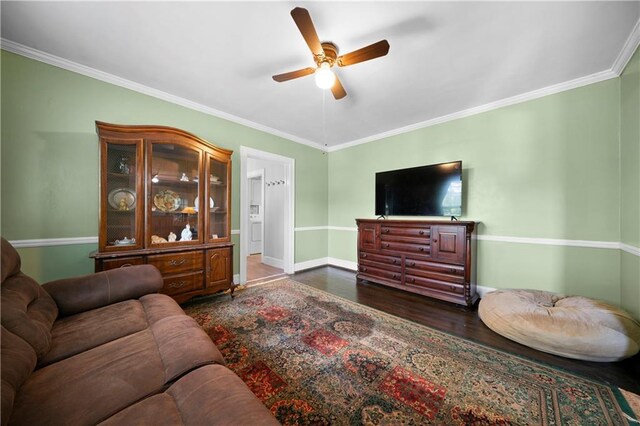 living room featuring baseboards, ceiling fan, crown molding, and wood finished floors