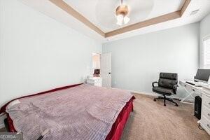 bedroom featuring a raised ceiling and carpet flooring