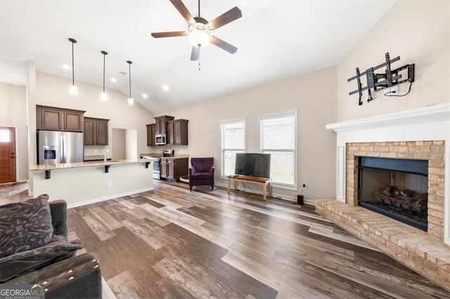 living room with ceiling fan, high vaulted ceiling, a fireplace, and dark hardwood / wood-style flooring