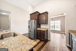 kitchen featuring stainless steel refrigerator with ice dispenser, sink, light stone counters, and dark hardwood / wood-style floors