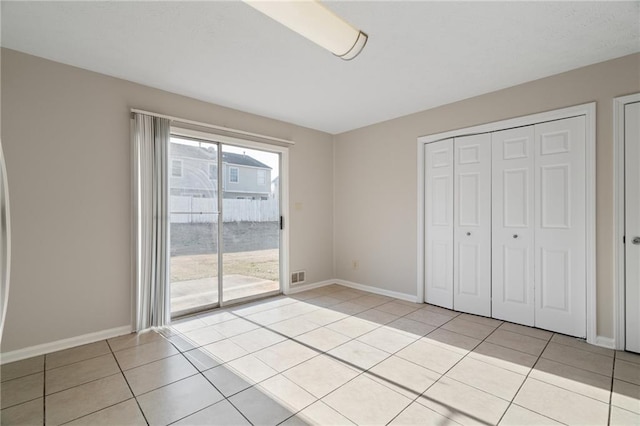 unfurnished bedroom featuring light tile patterned floors, access to outside, and a closet