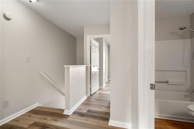 hall with hardwood / wood-style flooring and a textured ceiling