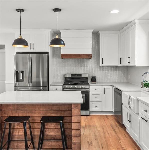 kitchen with white cabinetry, stainless steel appliances, and hanging light fixtures