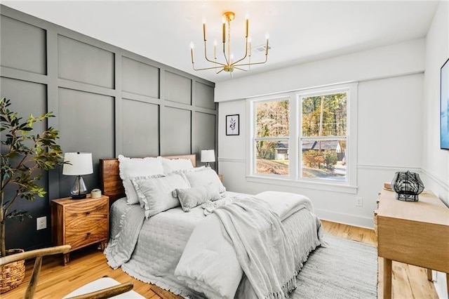 bedroom with an inviting chandelier and light wood-type flooring