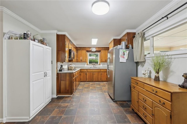 kitchen with freestanding refrigerator, black microwave, brown cabinets, light countertops, and stone finish flooring