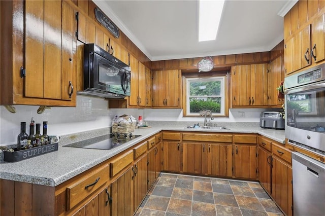 kitchen with black appliances, a sink, stone finish flooring, and brown cabinetry