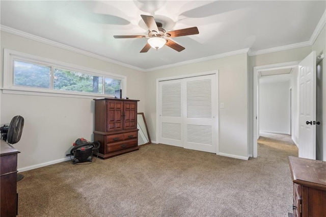 carpeted bedroom with a closet, ornamental molding, a ceiling fan, and baseboards