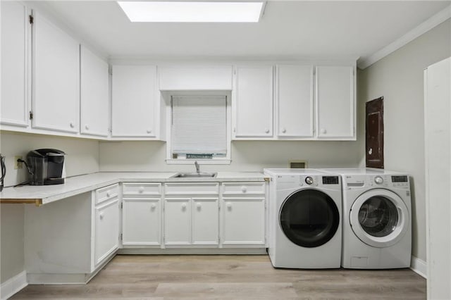 washroom featuring crown molding, washer and dryer, cabinet space, light wood-style flooring, and baseboards