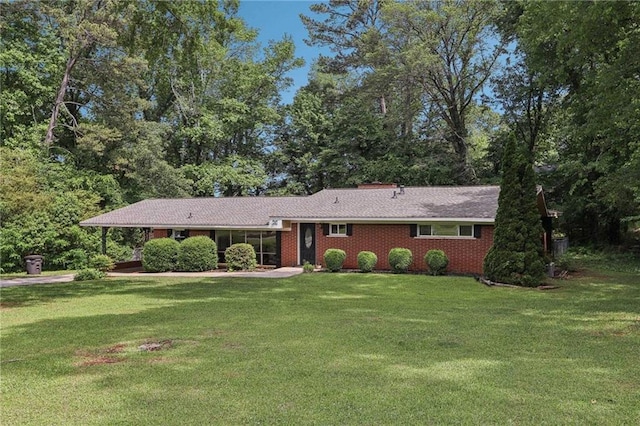 ranch-style home featuring a front lawn, brick siding, and a carport