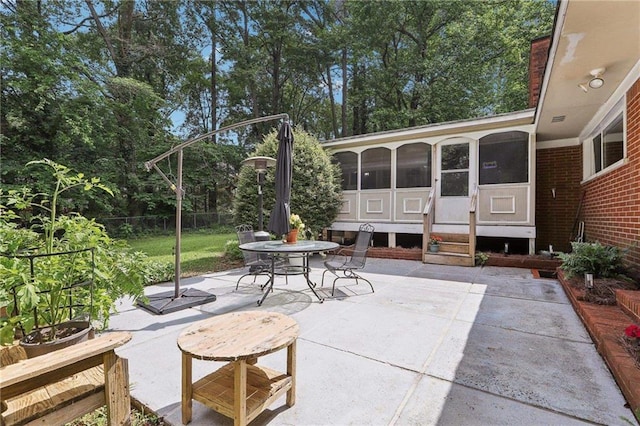view of patio / terrace with a sunroom, outdoor dining space, and fence