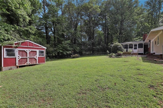 view of grassy yard featuring a sunroom, a storage shed, and an outdoor structure