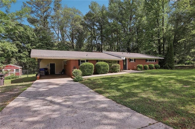 single story home featuring driveway, an attached carport, and view of wooded area