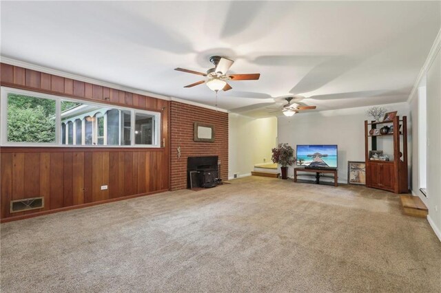 living area with a wood stove, a ceiling fan, carpet floors, baseboards, and wood walls