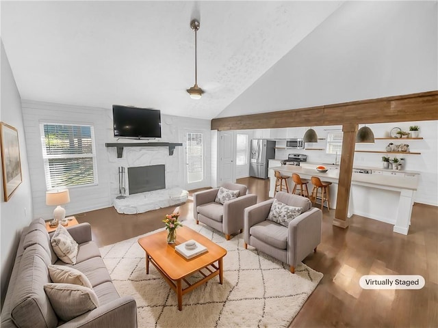 living area featuring light wood finished floors, a fireplace, and high vaulted ceiling