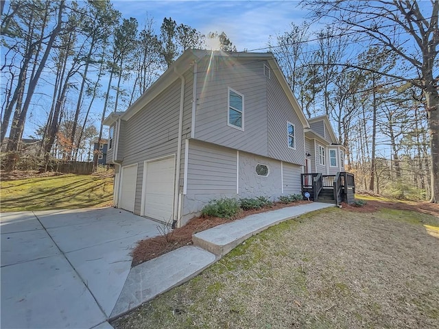 view of side of home with concrete driveway, a yard, and an attached garage